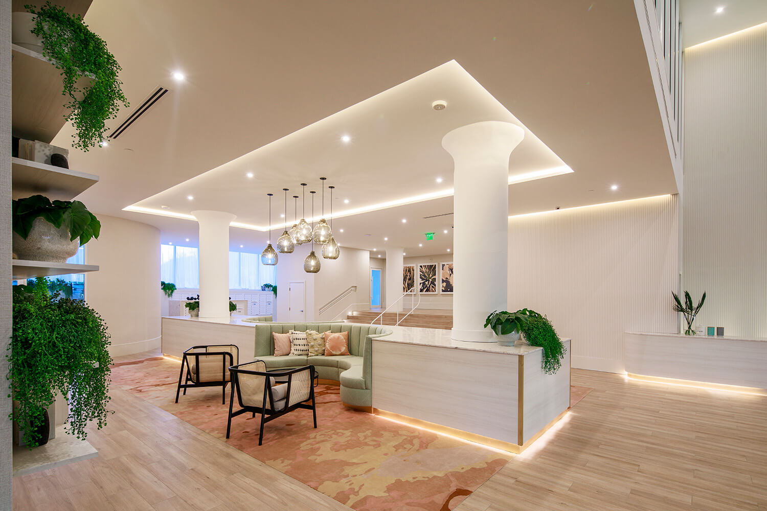 Hotel lobby with greenery, hanging lights, and lounge chairs 